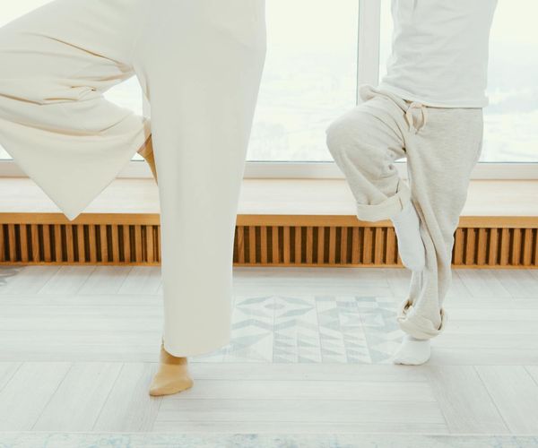 Person sitting comfortably on a yoga mat in a bright room.