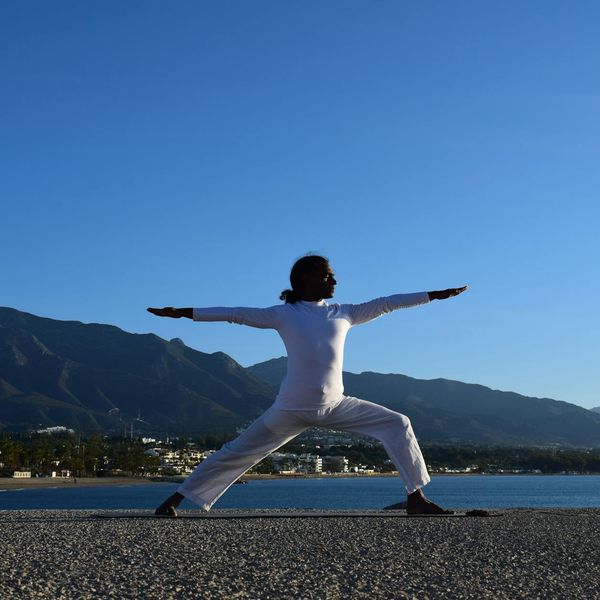 Silhouette of a person in a powerful yoga pose against a sunrise.